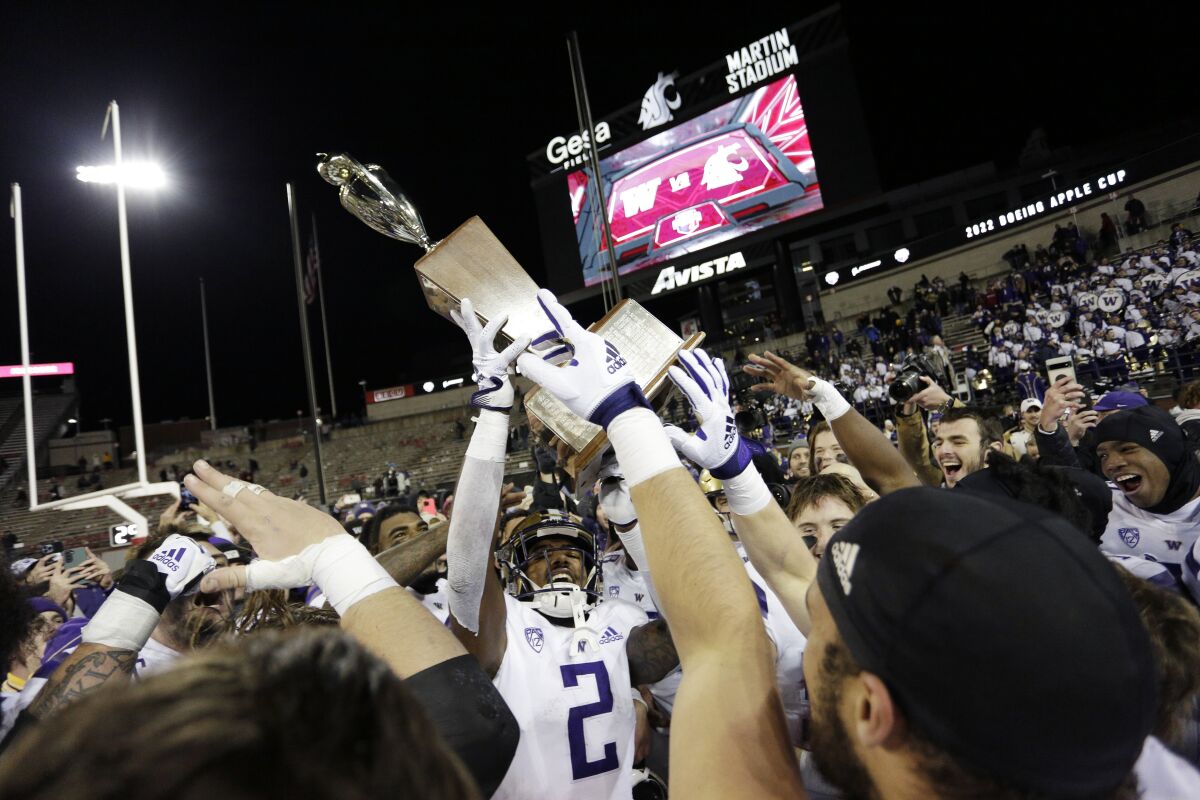 Washington players celebrate with the Apple Cup Trophy after their 51-33 win against Washington State in an NCAA college football game, Saturday, Nov. 26, 2022, in Pullman, Wash. (AP Photo/Young Kwak)
