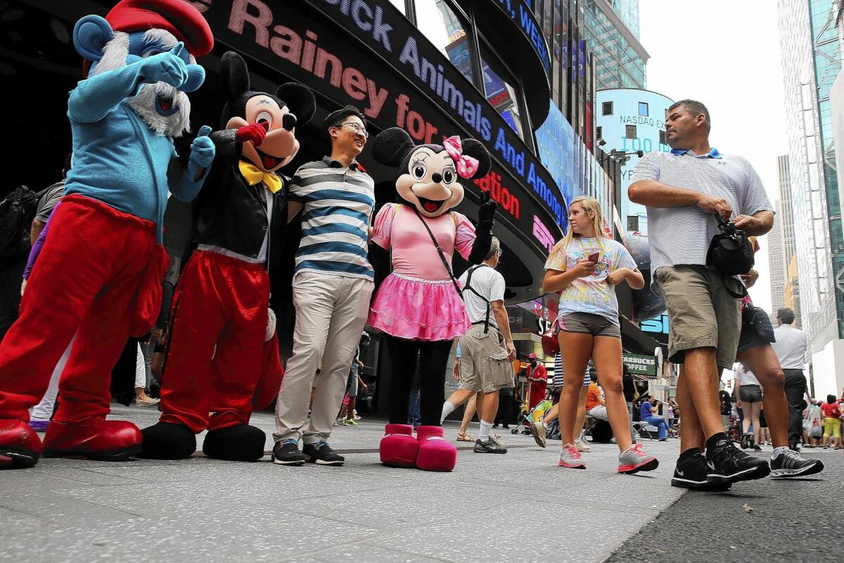 Costumed street performers pose with tourists for tips in Times Square in New York this week.