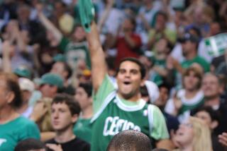 Celtics fans celebrate a playoff win as Kobe Bryant sits on the bench and puts his head in a towel in Boston on June 8, 2008.