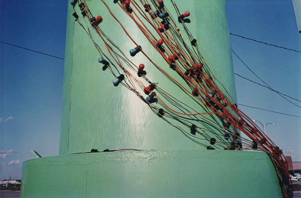 In this brightly hued shot by celebrated lensman William Eggleston, a strand of Christmas lights hangs on a jade-colored pole. It is Christmas without being Christmas.