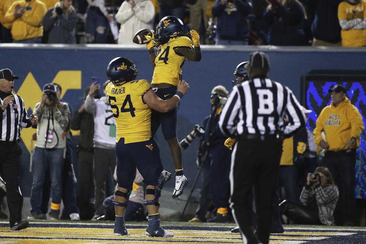 West Virginia offensive lineman Zach Frazier (54) and West Virginia running back Tony Mathis Jr. (24) celebrate Mathis' touchdown during the second half of the team's NCAA college football game against Baylor in Morgantown, W.Va., Thursday, Oct. 13, 2022. (AP Photo/Kathleen Batten)