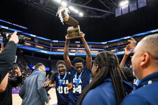 Mahamadou Diop holds up Division III state championship trophy for San Gabriel Academy.