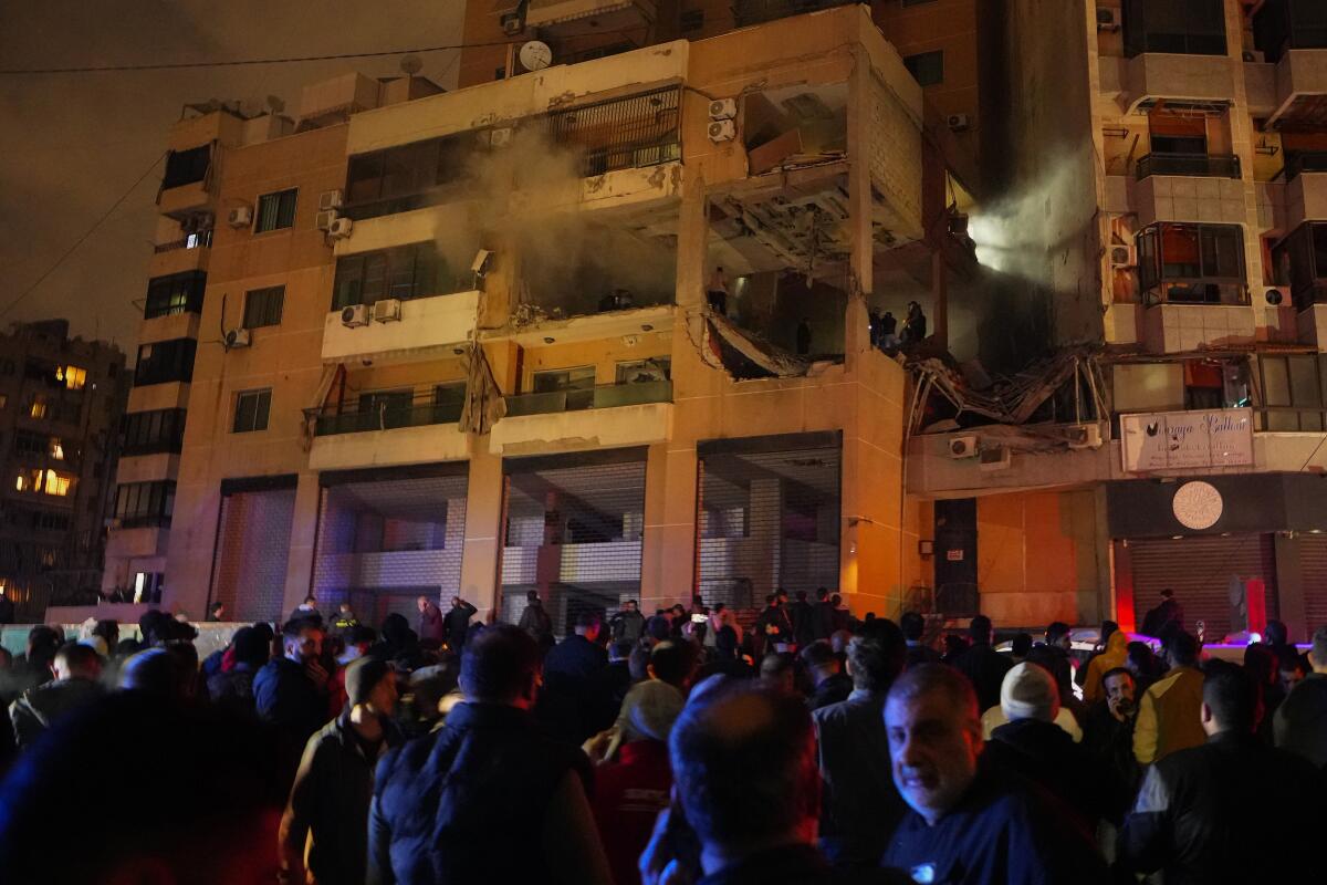 People gather outside a damaged multistory building 