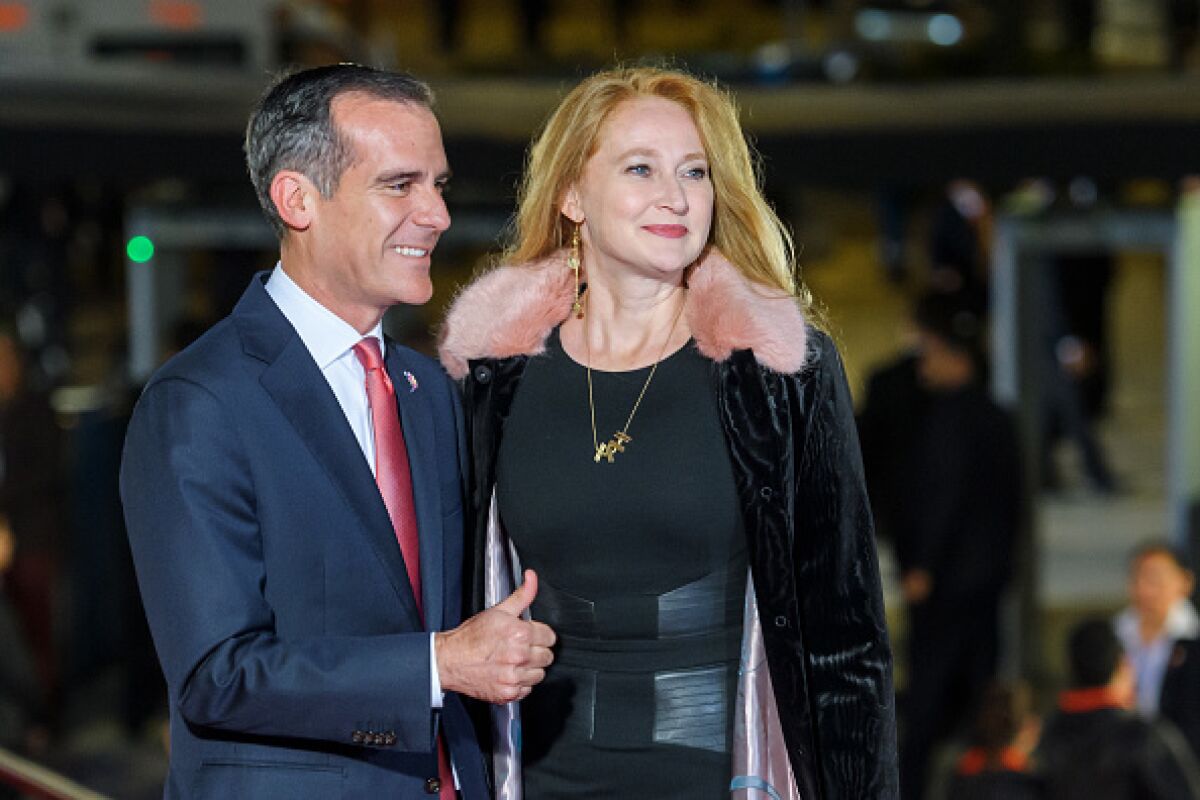 Mayor Eric Garcetti and First Lady Amy Wakeland smile and look to the side.
