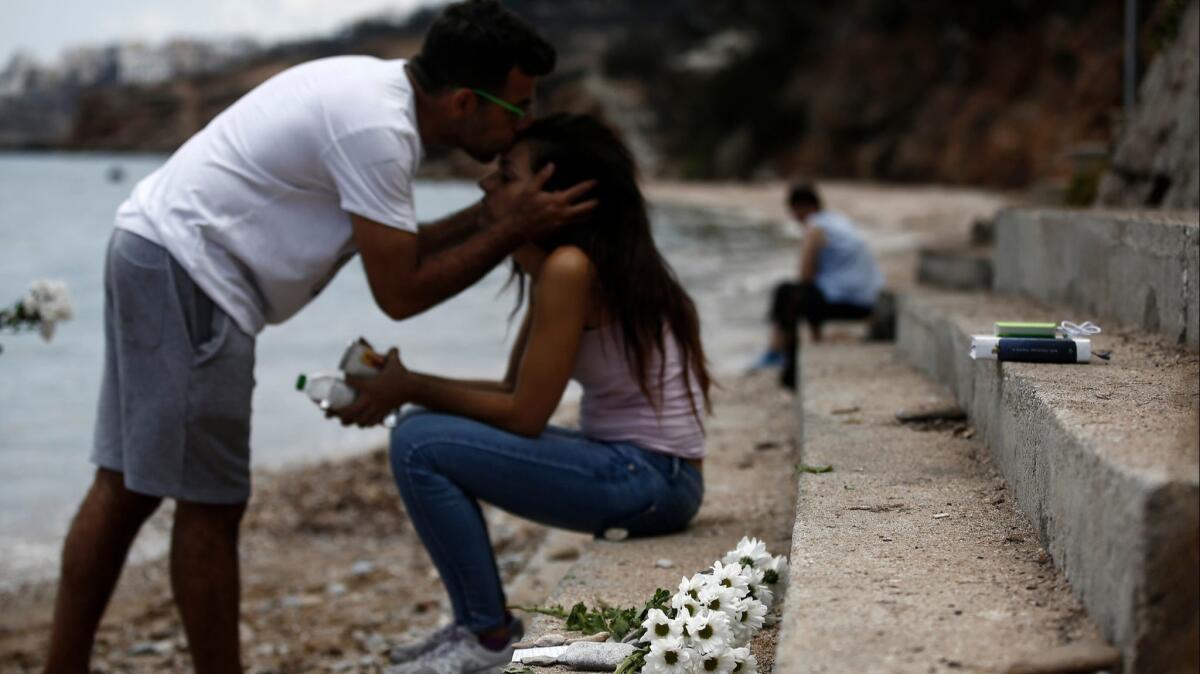 Dimitris Matrakidis kisses his sister Maria as flowers are placed at the point where a 6-month-old baby died after a forest fire in Mati, a northeast suburb of Athenson July 27, 2018.