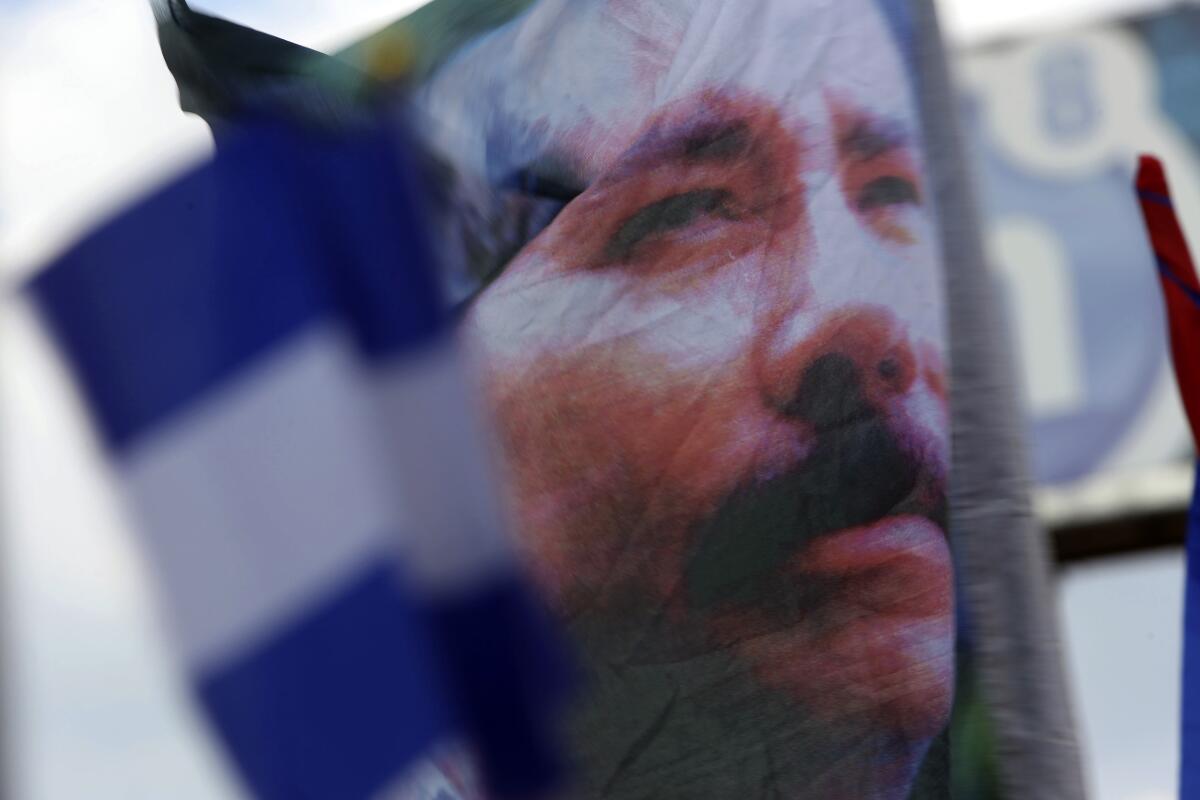 FILE - A banner emblazoned with an image of Nicaragua's President Daniel Ortega is waved by an Ortega supporter in Managua, Nicaragua, April 30, 2018. Ortega’s opponents regularly compare him to dictator Anastasio Somoza for his authoritarian tendencies, and also accuse him of dynastic ambitions. (AP Photo/Alfredo Zuniga, File)