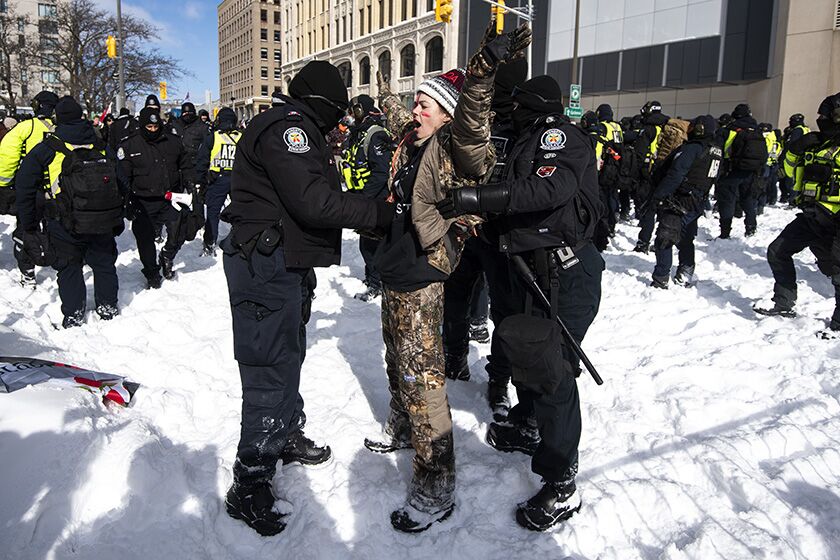 A protester sings the Canadian national anthem as she is arrested in Ottawa on Friday.