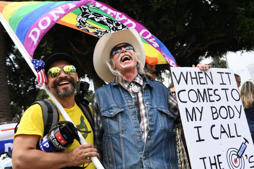 LOS ANGELES, CA. August 29, 2021: Two men share a laugh at a rally near the Santa Monica Pier for a "worldwide rally for freedom" Sunday. Hundreds of people attended the event at Tongva Park. (Wally Skalij/Los Angeles Times)