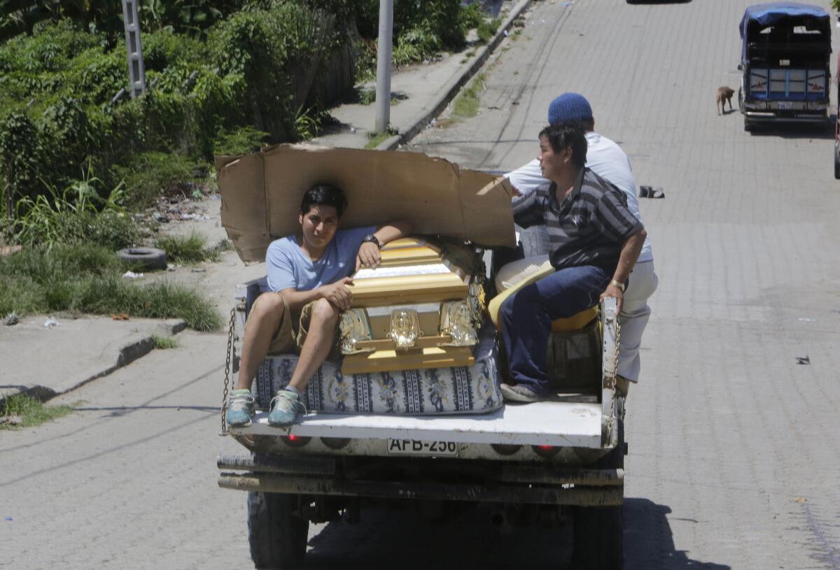 People carry an empty coffin on a pickup truck as they drive to collect the body of an earthquake victim in Pedernales, Ecuador.