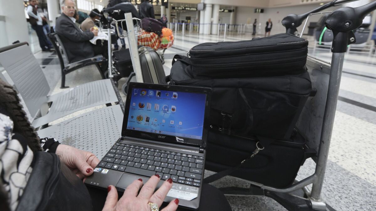 A Syrian woman traveling to the United States through Amman, Jordan, opens her laptop before checking in at Beirut's international airport.