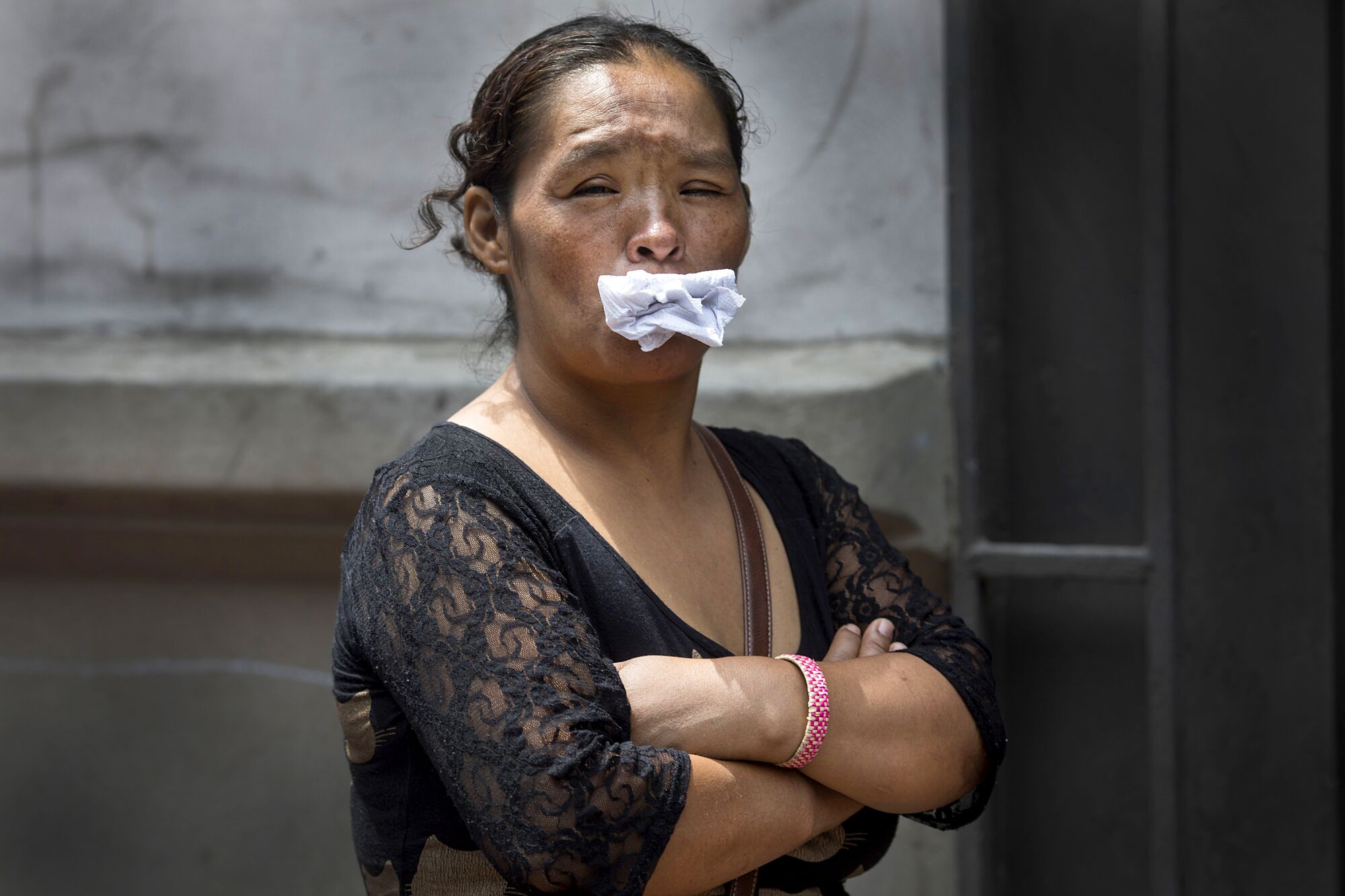 PERU: A woman stuffs paper into her mouth, her alternative to a face mask, as she waits in line for a free lunch from a charity organization that helps the homeless in Lima.