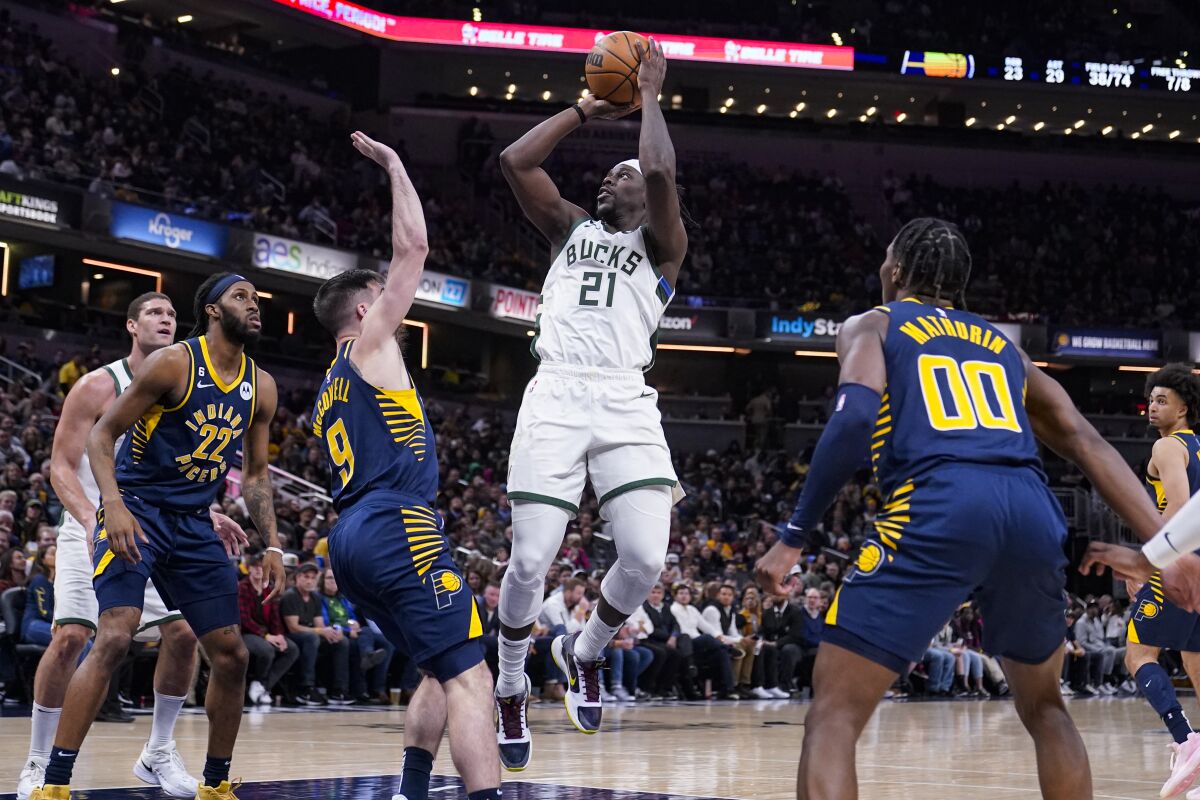 Milwaukee Bucks guard Jrue Holiday (21) shoots over Indiana Pacers guard T.J. McConnell (9) during the second half of an NBA basketball game in Indianapolis, Wednesday, March 29, 2023. (AP Photo/Michael Conroy)
