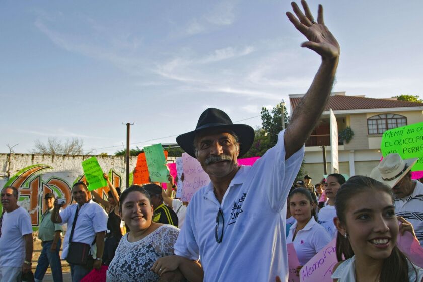 Jose Manuel Mireles, a leader of a vigilante self-defense group in Mexico's MichoacÃ¡n state, waves during a march in Tepalcatepec to celebrate the first anniversary of the groups' founding. The groups have been ordered to lay down their weapons.