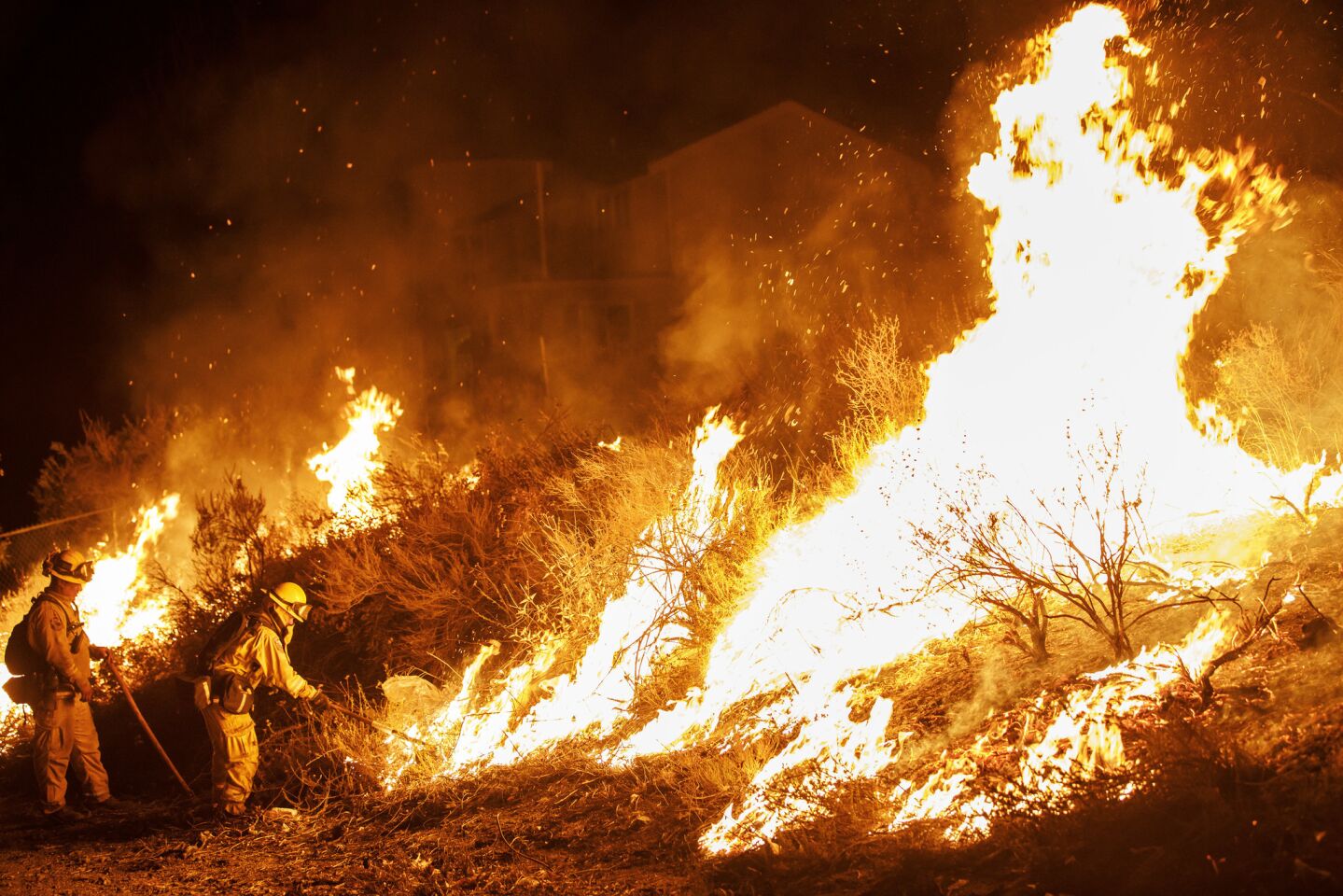 Firefighters conduct a burn operation to remove fuel around homes on Grand Avenue as the Holy fire grows to more than 10,000 acres.