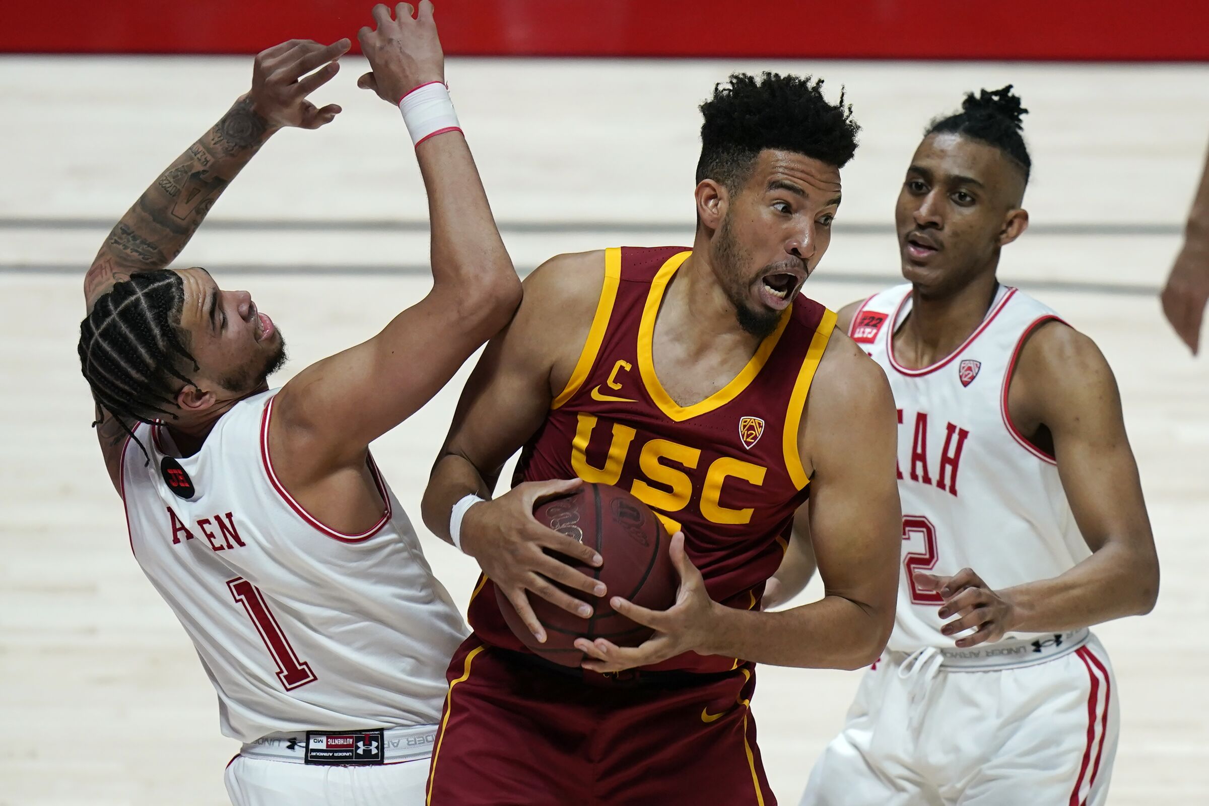 USC forward Isaiah Mobley pulls down a rebound between Utah's Timmy Allen and Ian Martinez.