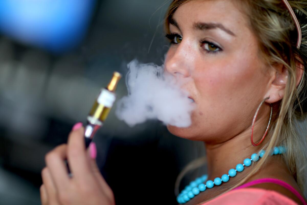 A woman uses an electronic cigarette in Miami. A new study from the Centers for Disease Control and Prevention finds that 13% of U.S. adults have tried e-cigarettes and 4% use them regularly.