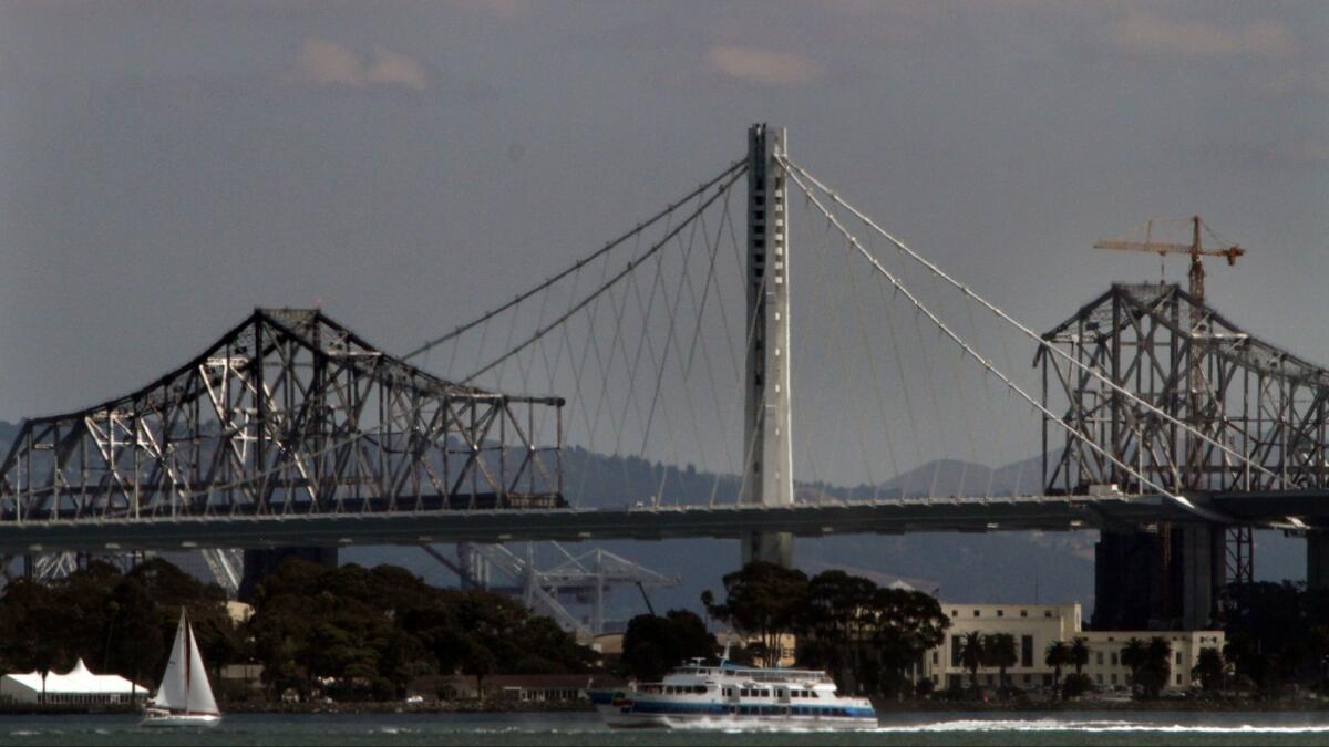 The new Bay Bridge rises as the old one is dismantled in San Francisco Bay on September 24, 2014. The $6.4 billion bridge will ultimately cost taxpayers more than $13 billion after paying off the debt to private financial institutions.