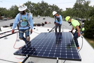 LOS ANGELES, CA - JUNE 18: Sal Miranda, left, supervisor, Lee Kwok, solar installer supervisor, and Juan Alcantara, intern/trainee, of GRID Alternatives, a nonprofit, install solar panels that will generate 5 kilowatts of energy at a low-income home in Watts on Friday, June 18, 2021 in Los Angeles, CA. A total of 15 327 watt panels were placed on the roof. (Gary Coronado / Los Angeles Times)