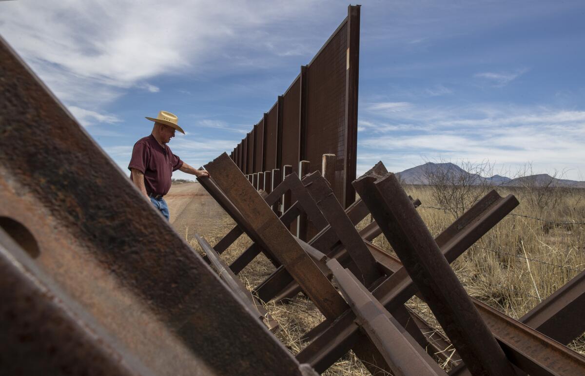 Gary Thrasher looks over a Normandy vehicle barrier near the San Pedro River bordering his friend and fellow rancher John Ladd's property in Cochise County, Ariz., on March 2.