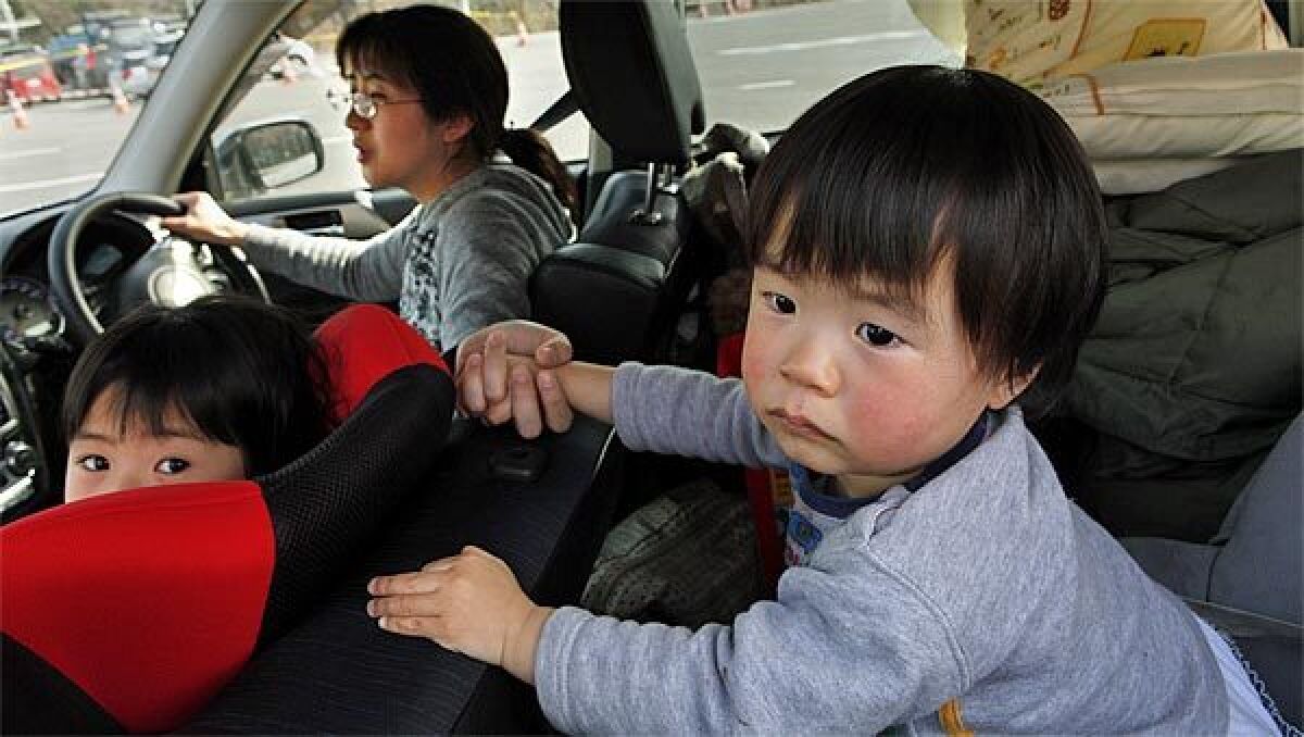 Mari Kano, age 33, holds her young son's hand as she and her two children flee their home in Fukushima.