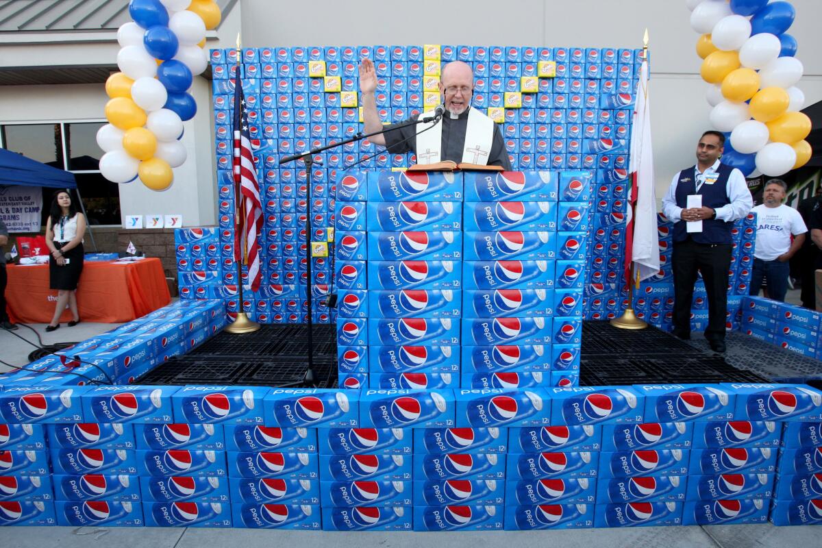 On a stage constructed from soda cases and pallets, Father Nicholas of St. Patrick's Church in North Hollywood gives his blessings to the new Walmart Supercenter during its grand opening on N. Victory Place on Wednesday, June 22, 2016.