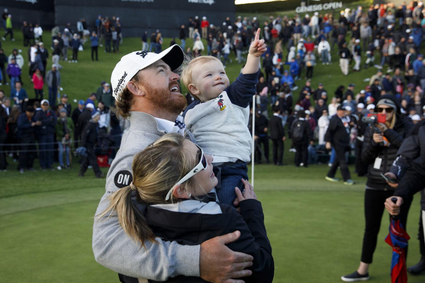 J.B. Holmes hugs his son Tucker and wife Erica after winning on the 18th hole the Genesis Open golf tournament at the Riviera Country Club.