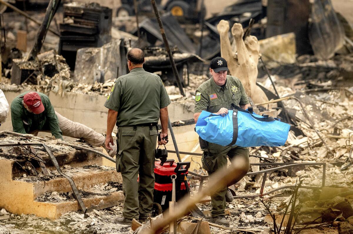 A Siskiyou County sheriff's deputy carries the body of a McKinney fire victim from a destroyed home