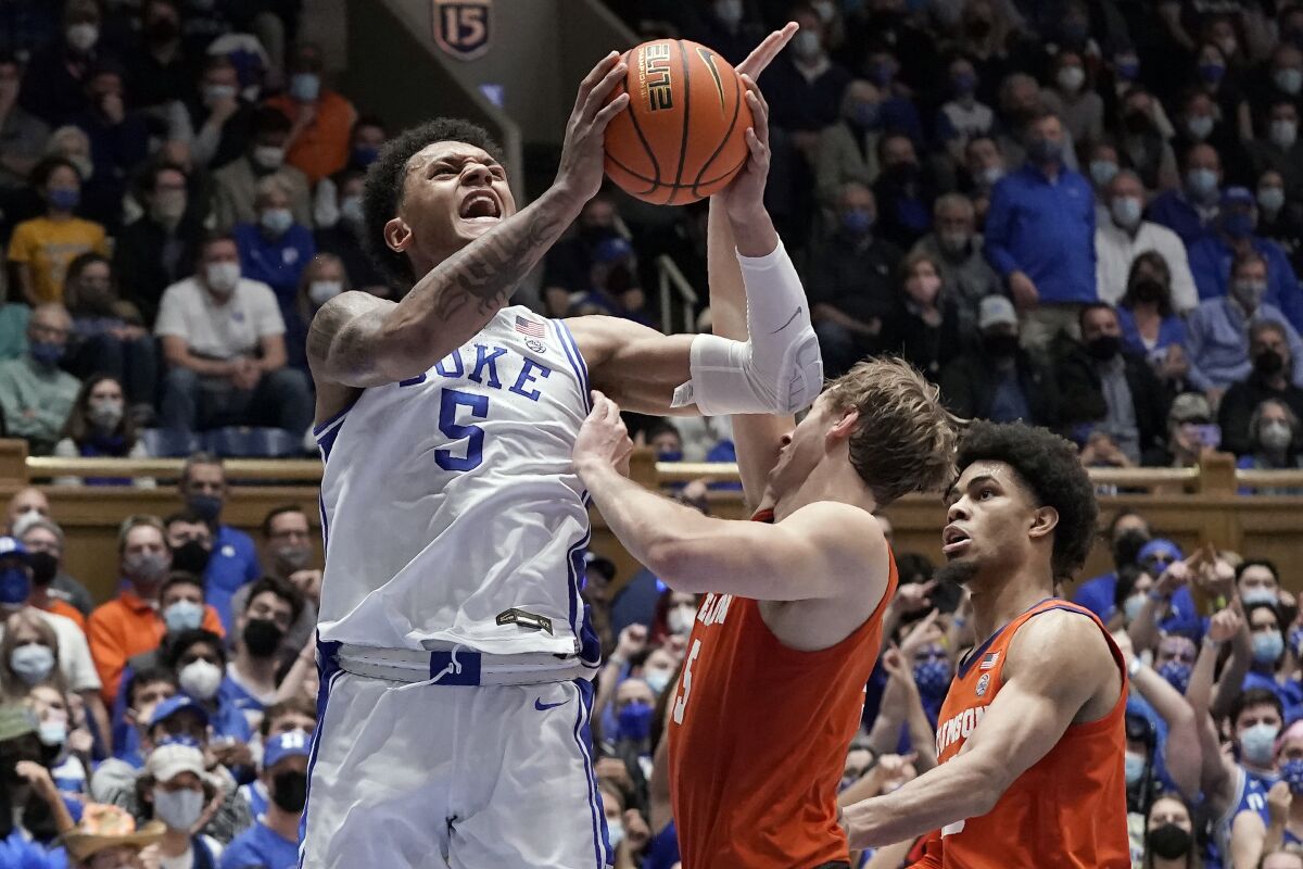 Duke forward Paolo Banchero (5) shoots while Clemson forward Hunter Tyson and guard David Collins, right, defends during the second half of an NCAA college basketball game in Durham, N.C., Tuesday, Jan. 25, 2022. (AP Photo/Gerry Broome)