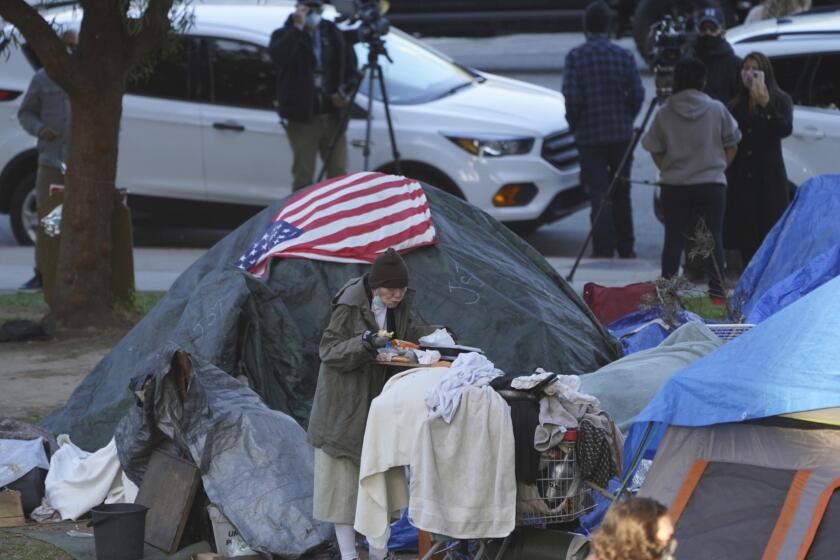 FILE - In this March 24, 2021, file photo a woman eats at her tent at the Echo Park homeless encampment at Echo Park Lake in Los Angeles. California Gov. Gavin Newsom announced a $12 billion plan Tuesday, May 11 to confront the state's homelessness crisis. (AP Photo/Damian Dovarganes, File)