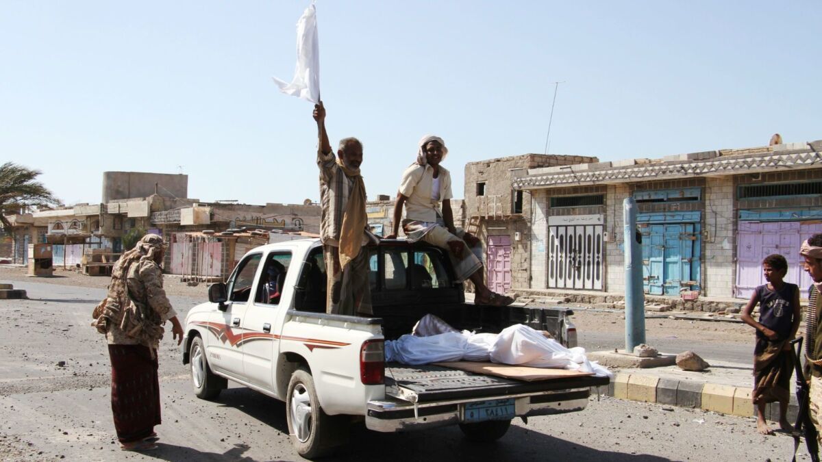 A Yemeni man standing on a pickup carrying a body waves a white flag toward fighters loyal to the Saudi-backed Yemeni president in the western coastal town of Mokha in 2017.