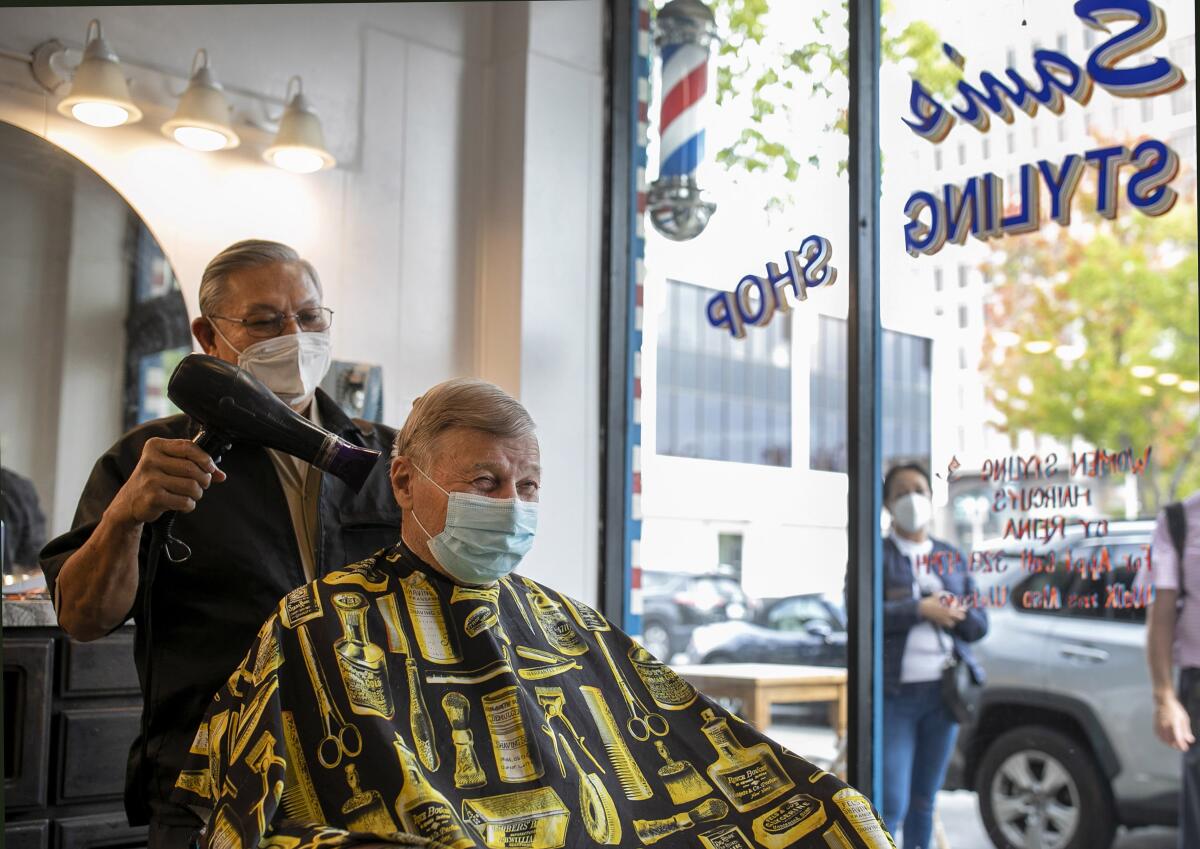 A barber in a mask works on a client in a mask.