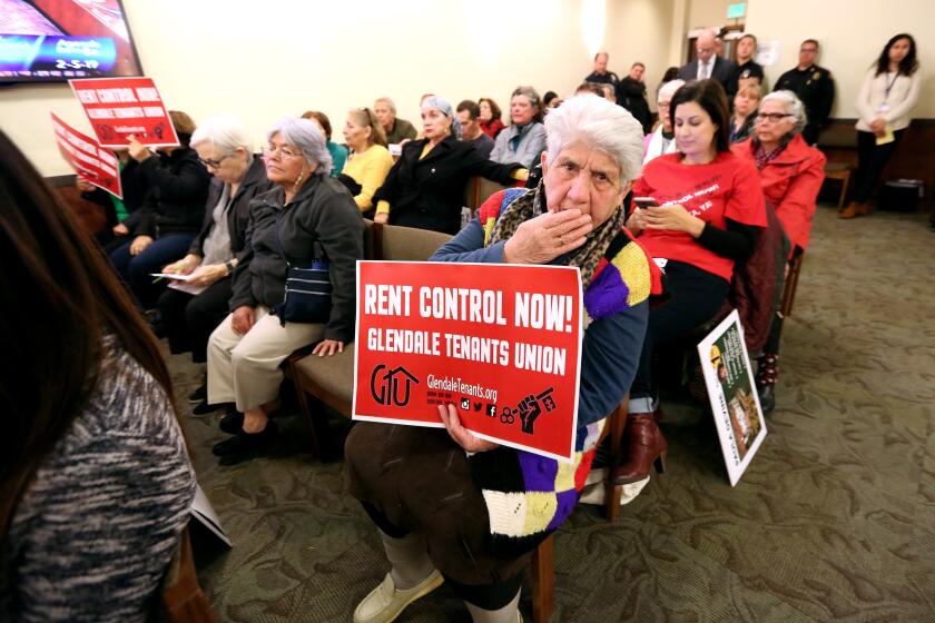 A woman holds a Glendale Tenants Union sign during the council meeting at Glendale City Hall on Tuesday, Feb. 5, 2019. The union wants rent control in the city.
