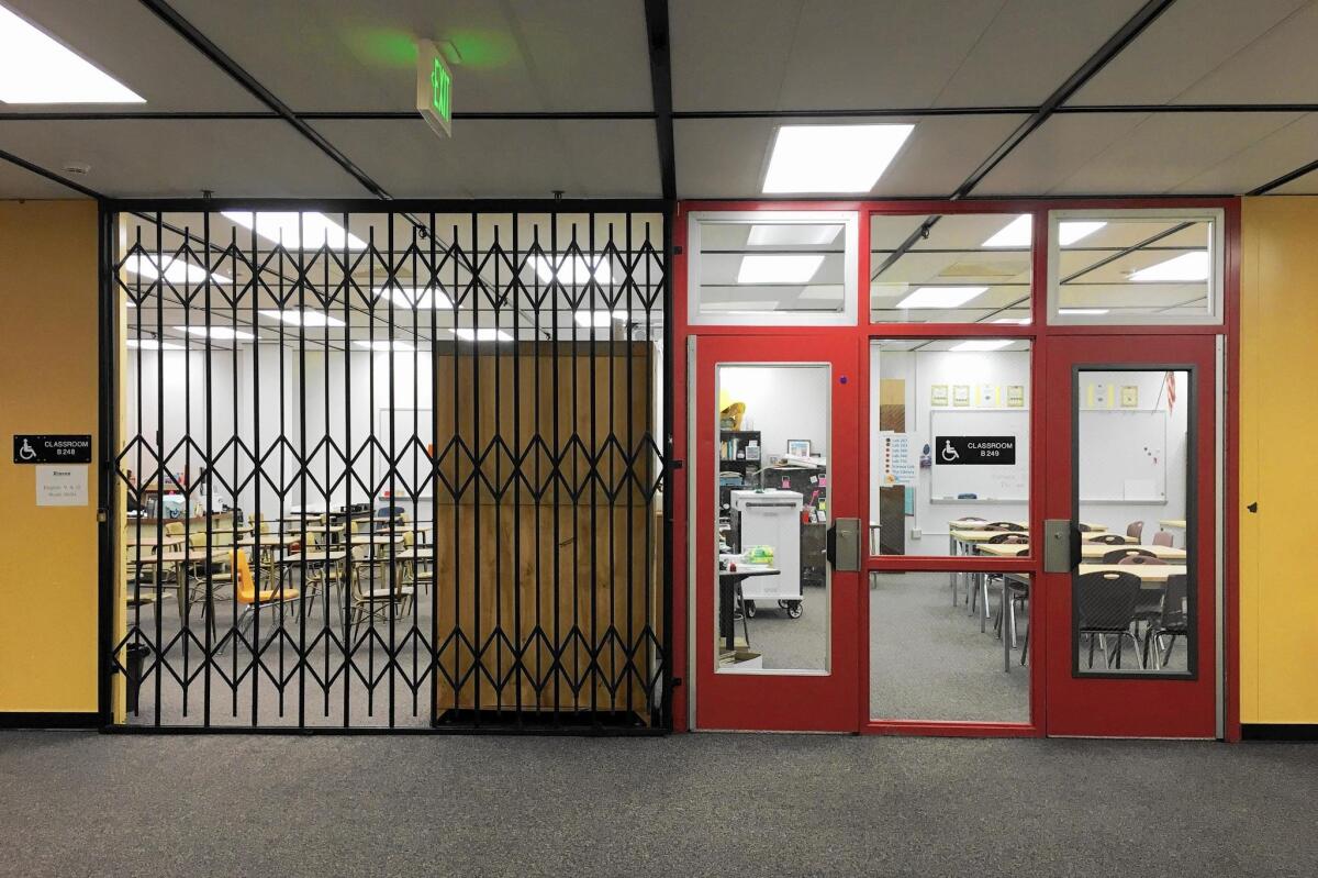 An Estancia High School classroom with folded gates beside one with windows and lockable doors.
