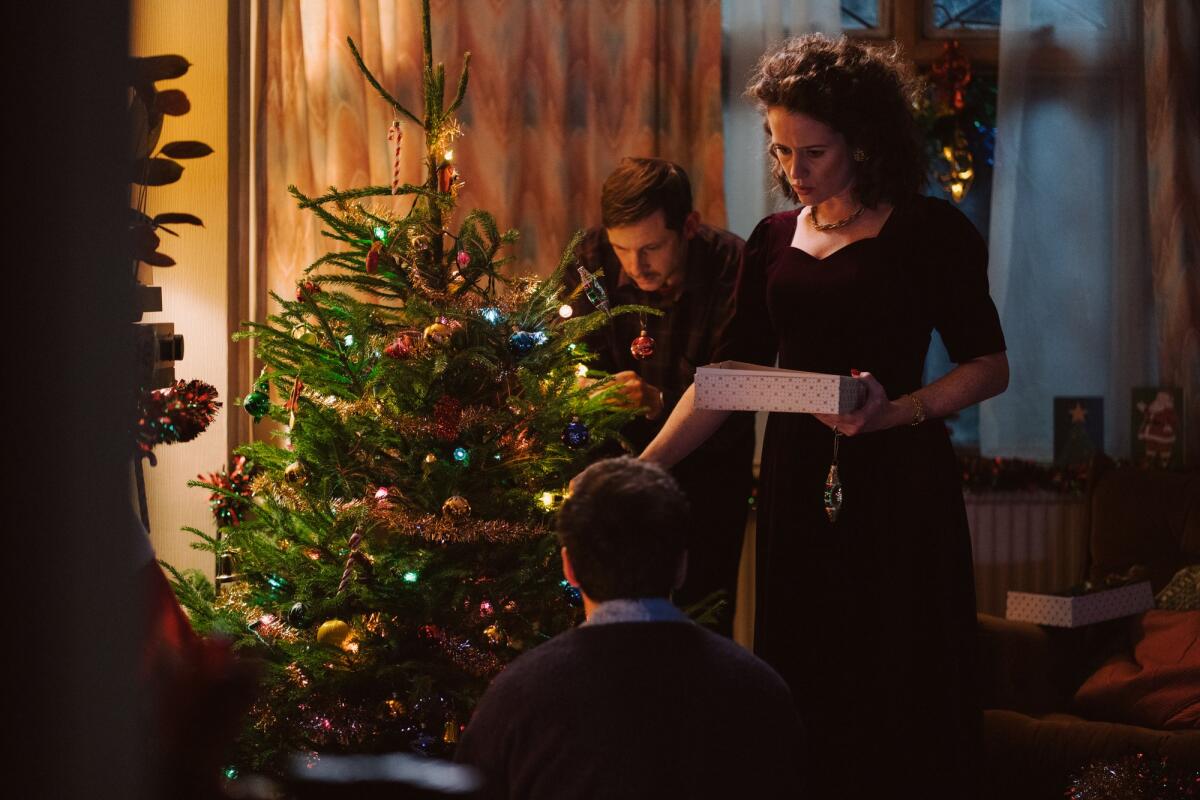 A man and a woman decorate a Christmas tree in the movie "All of Us Strangers."
