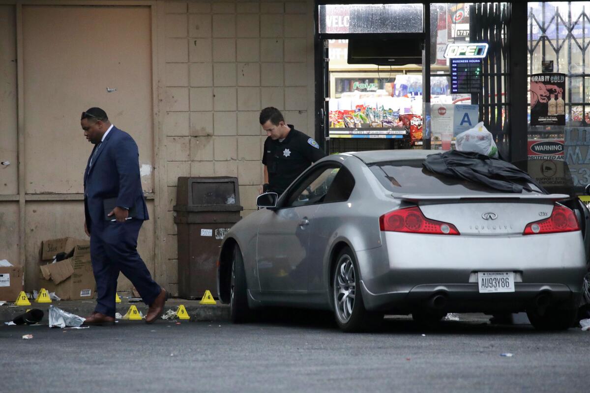 Detectives on Friday investigate the scene of a police shooting outside a San Bernardino liquor store. 