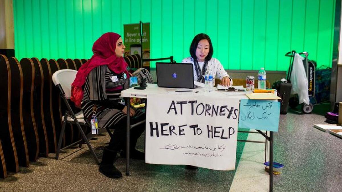 Volunteer translator Nour Our, left, and volunteer attorney Kat Choi sit in the arrivals area at LAX.