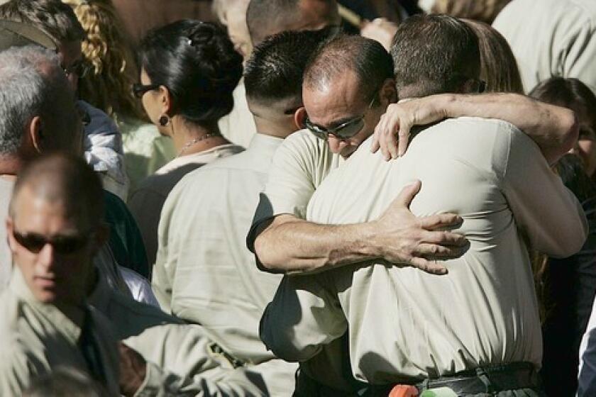 Two U.S. Forest Service firefighters embrace after the funeral for Capt. Mark Loutzenhiser at Idyllwild School in Idyllwild.