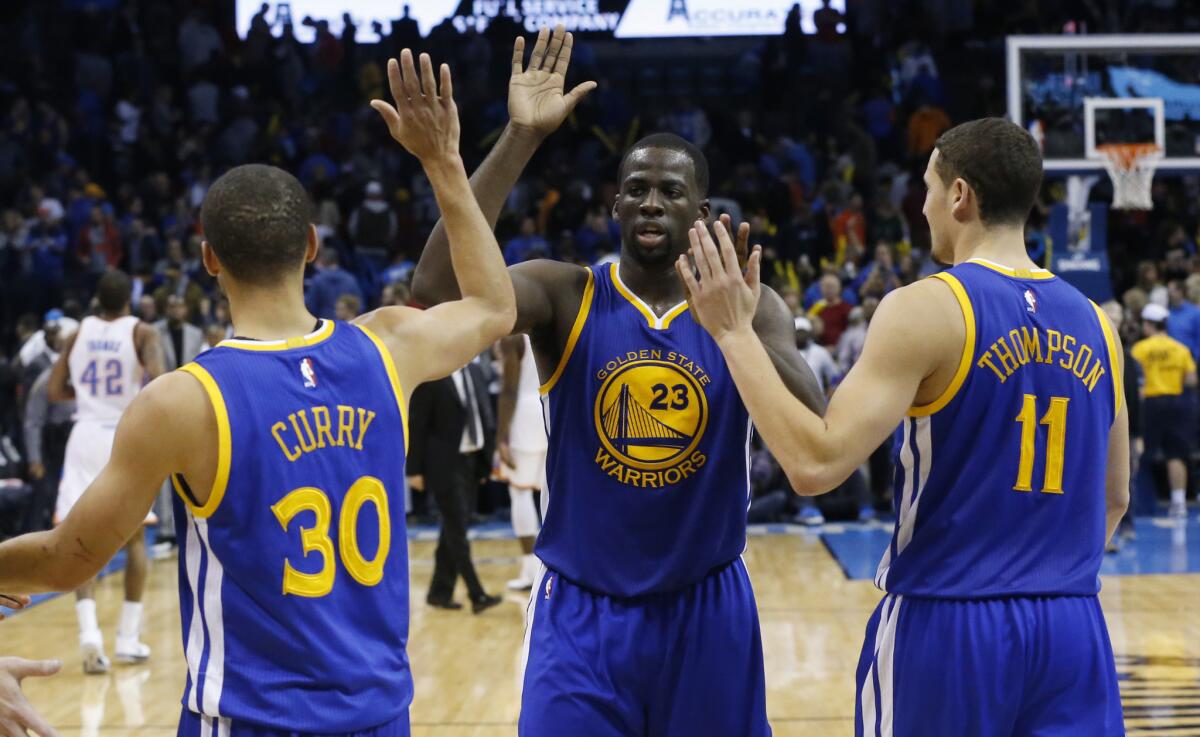 Golden State Warriors Stephen Curry (30), Draymond Green, center, and Klay Thompson (11) celebrate after beating the Oklahoma City Thunder, 91-86, on Nov. 23.