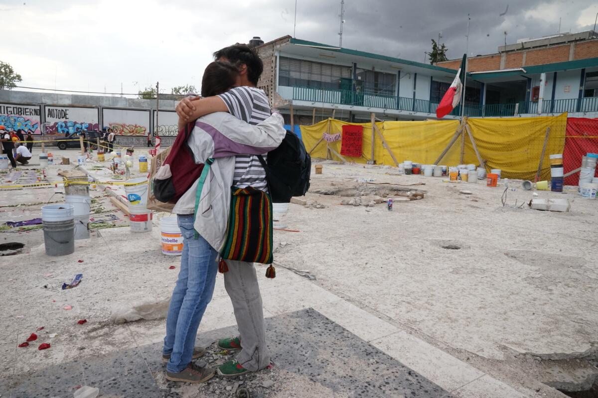Giselle Mejia, 23, and David Montoya, 32, students at National Autonomous University of Mexico, hug in shock as they stand near the site of the collapsed building.