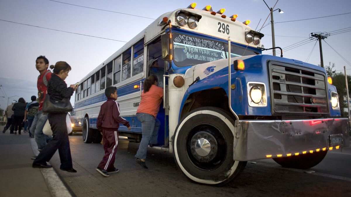 Riders board a bus in front of the Universidad Autonoma de Baja California in Tijuana. A future Bus Rapid Transit system is expected to eventually replace older buses throughout the city.