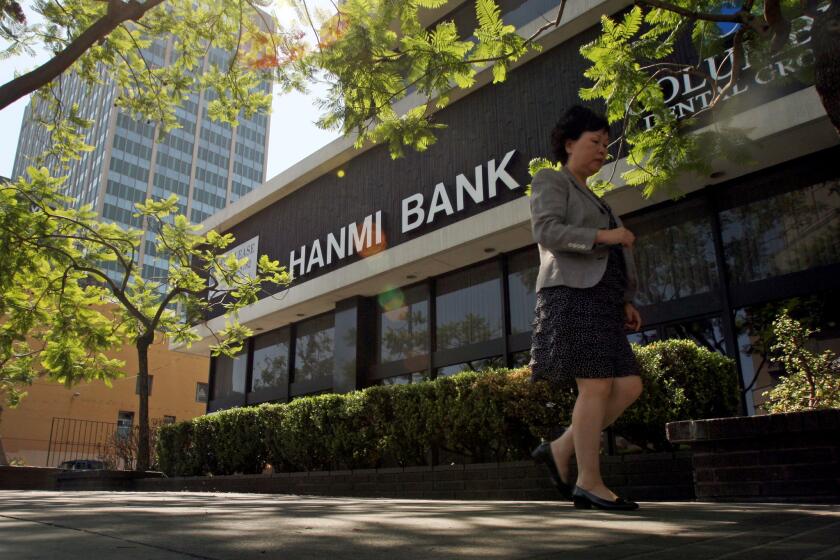 A passerby walks near the Hanmi bank building in L.A.'s Koreatown. The bank has withdrawn its proposed merger with rival Korean American lender BBCN.