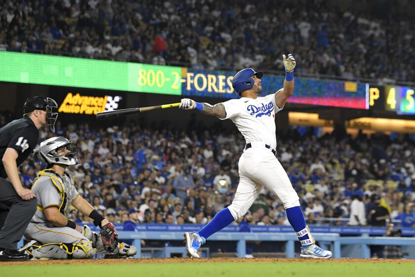Los Angeles Dodgers' David Peralta, right, hits a solo home run as Pittsburgh Pirates catcher Austin Hedges, center, and home plate umpire Clint Vondrak watch during the fifth inning of a baseball game Wednesday, July 5, 2023, in Los Angeles. (AP Photo/Mark J. Terrill)