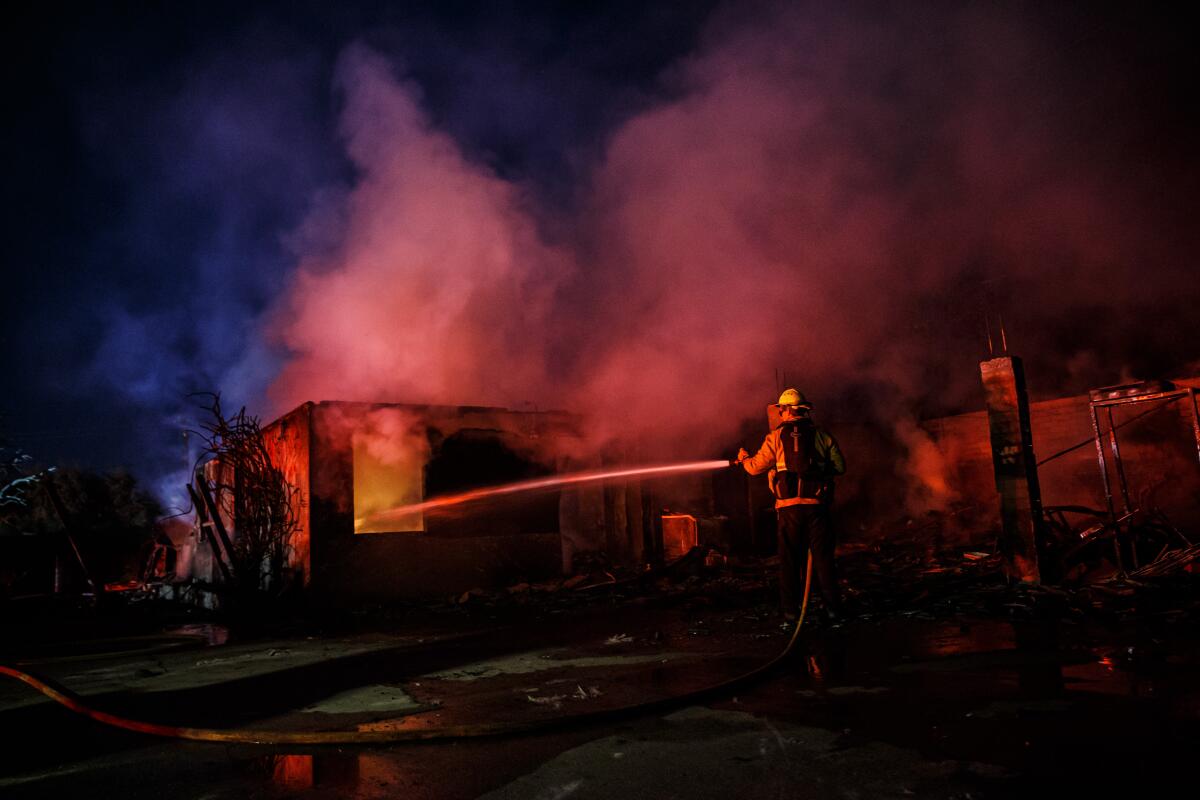 Firefighters mop up wreckage of a home destroyed by the Hillside fire Oct. 31 in San Bernardino.