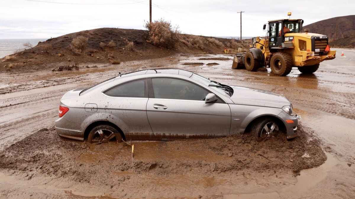 A car gets stuck in mud on Pacific Coast Highway, south of Mulholland, in Malibu Thursday morning after rain showers doused the Southland for a second straight day, triggering some mudslides and debris flows.