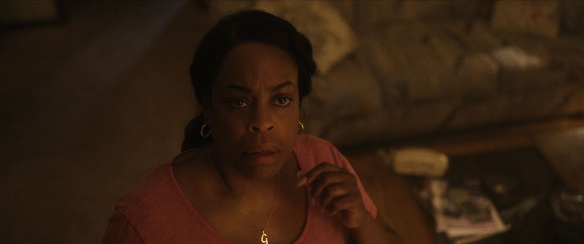 A woman stands in her apartment looking concerned in a scene from "Dahmer -- Monster: The Jeffrey Dahmer Story."