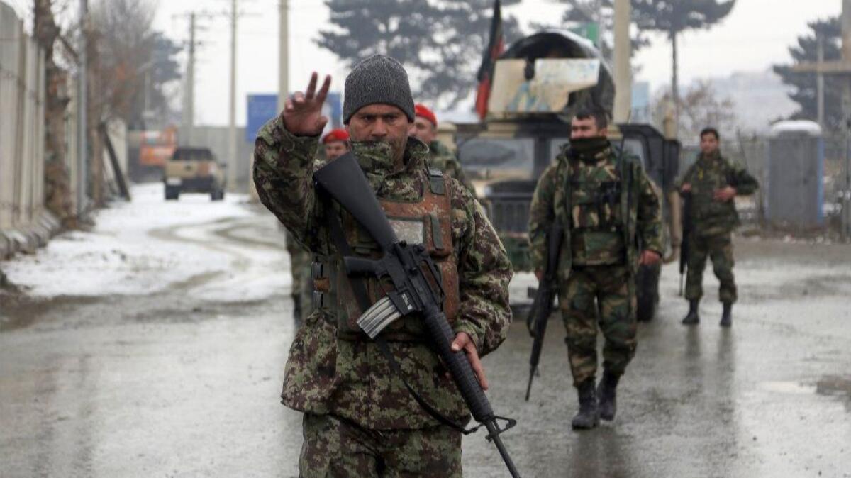 Afghan soldiers stand guard at the entrance to a military academy that was attacked Monday in Kabul.