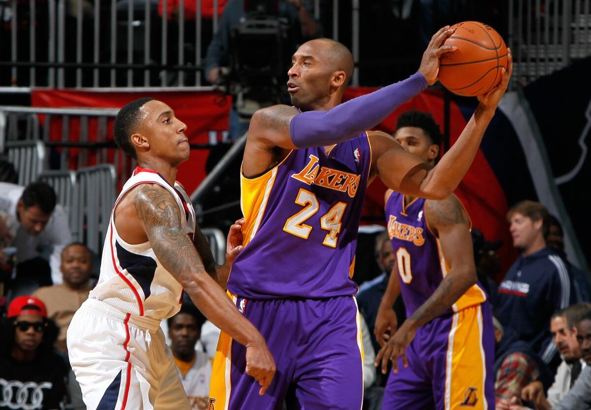 Lakers star Kobe Bryant, right, tries to pass around Atlanta Hawks guard Jeff Teague.