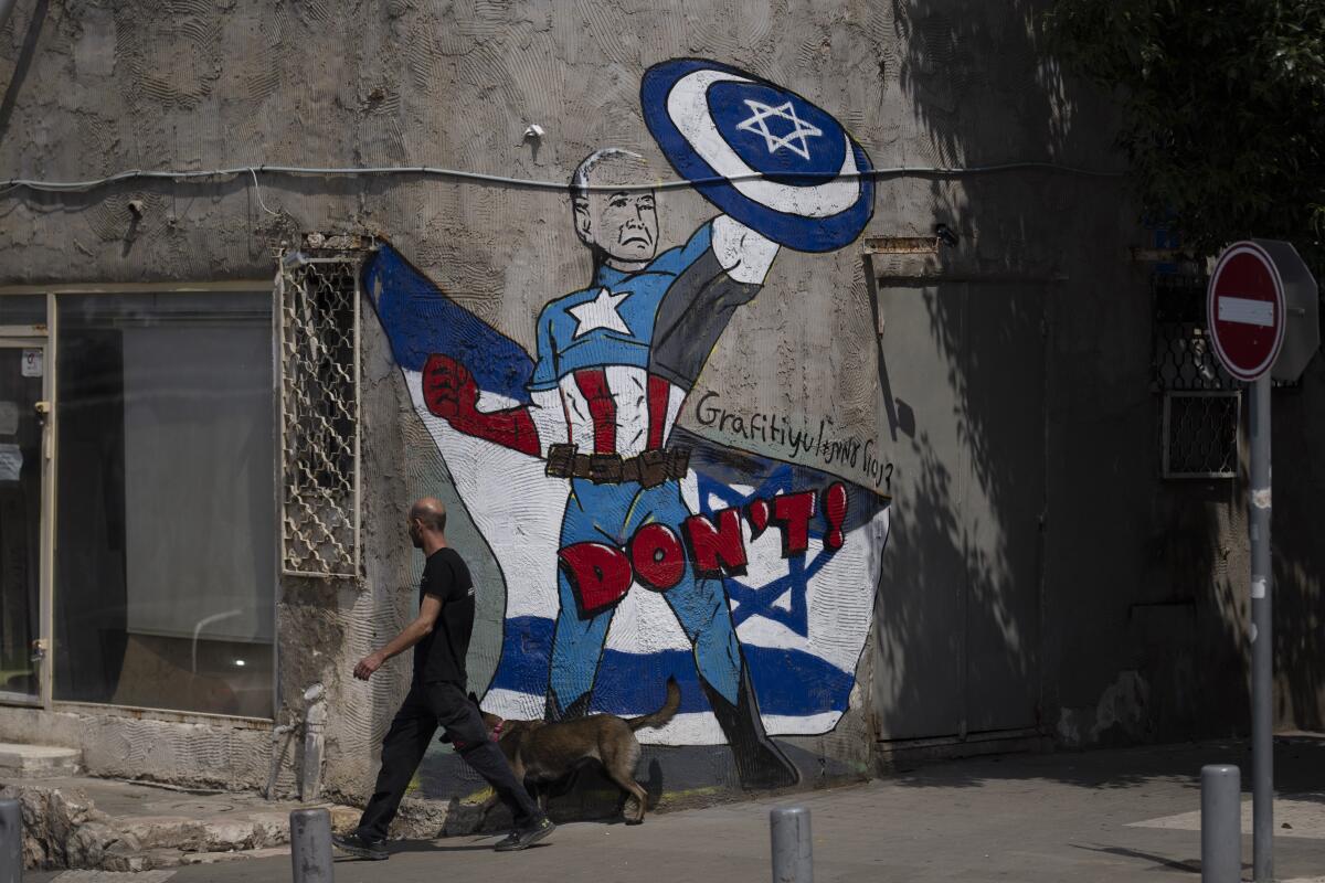 A man walks past a mural depicting President Biden as Captain America with the warning "Don't."