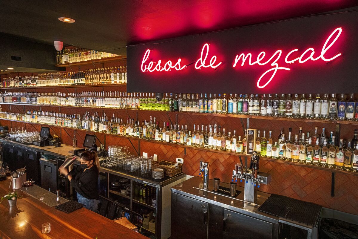 Tthe bar at Madre, in Torrance, features the words "besos de mezcal" in pink neon.