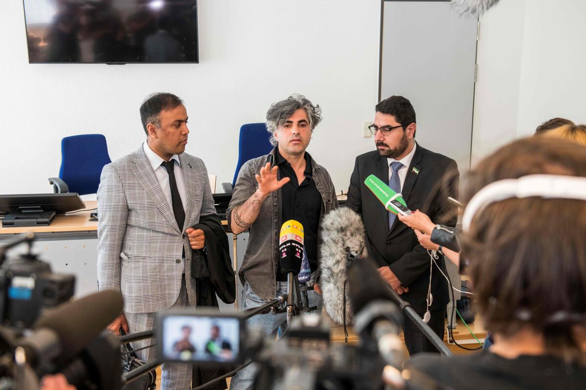 Attorney Khubaib-Ali and co-plaintiffs Feras Fayyad and Mohamad Alshaar answer journalists' questions outside the courtroom during a break in a trial against two Syrian defendants accused of state-sponsored torture in Syria, on April 23, 2020 in Koblenz, Germany.